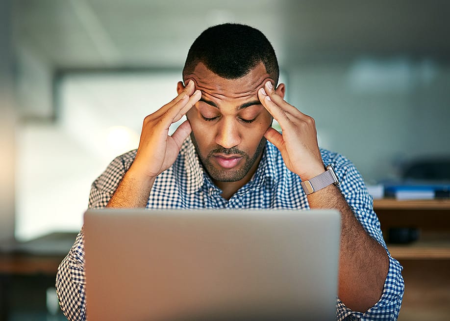 A stressed businessman facing a laptop. — PeopleImages // Shutterstock