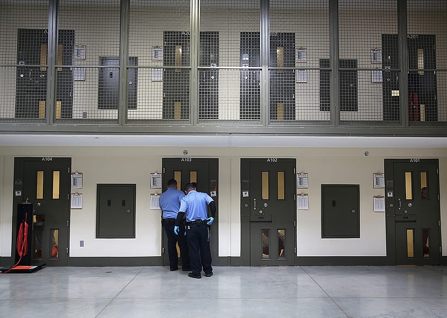 Guards prepare to escort an immigrant detainee from his 'segregation cell' back into the general population at the Adelanto Detention Facility on November 15, 2013 in Adelanto, California. — John Moore // Getty Images