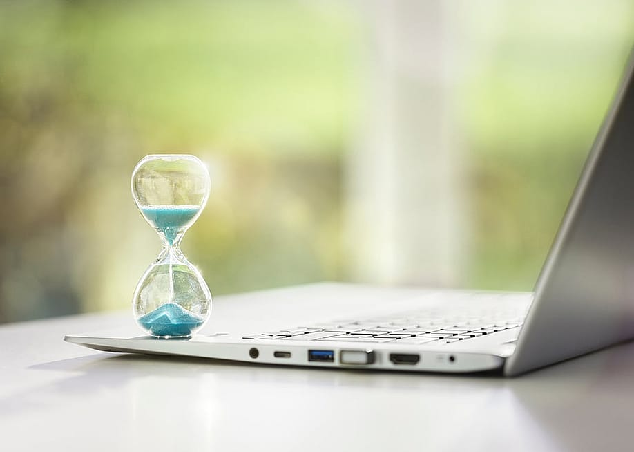 A small hourglass on top of a laptop as a concept of deadline and time management. — Brian A Jackson // Shutterstock