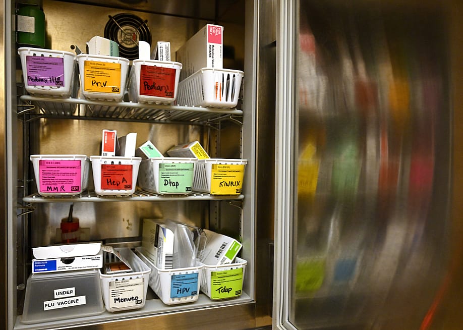 A small open refrigerator with shelves of baskets of vaccines at a health clinic. — Joshua Lott // The Washington Post via Getty Images