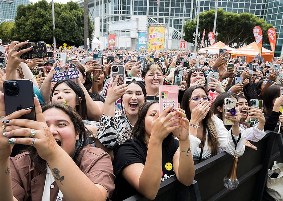 A crowd of fans holding their phones up and cheering outside the Crypto.com Arena for a K-Pop concert in Los Angeles, California. — Sam the Leigh // Shutterstock