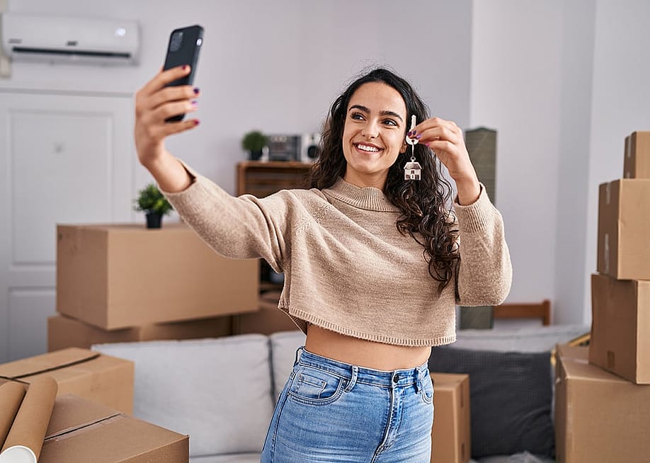 A young woman taking a selfie with her new home's keys. — Krakenimages.com // Shutterstock