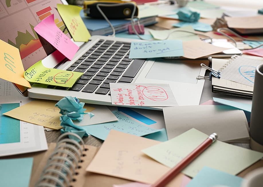 Sticky notes mess on top of a laptop on a working desk. — New Africa // Shutterstock