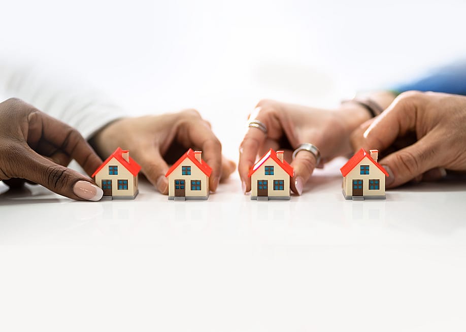 People's hand holding tiny models of houses. — Andrey_Popov // Shutterstock
