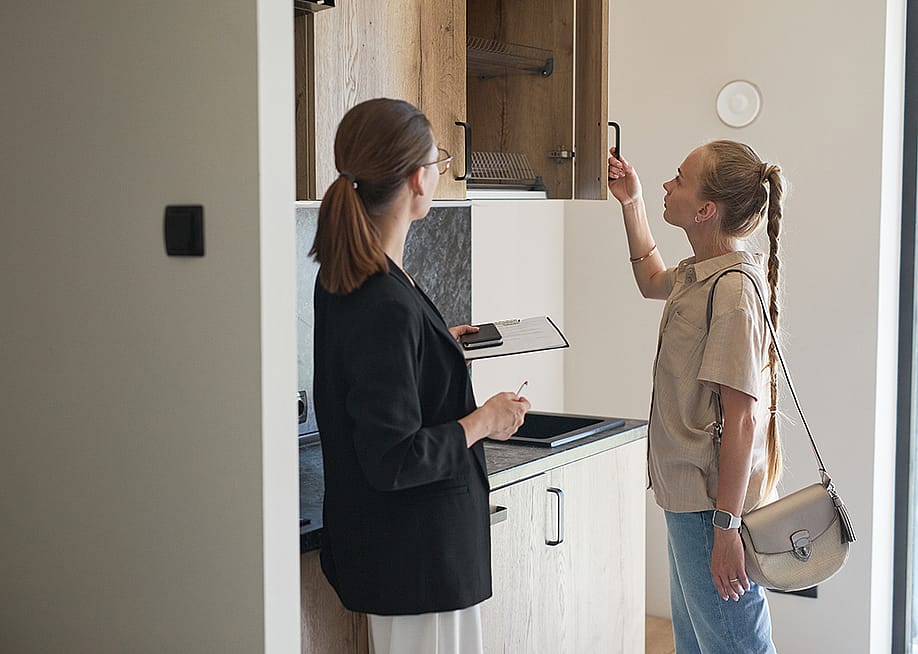 A young woman checking cabinets of an apartment with a female real estate agent. — SeventyFour // Shutterstock