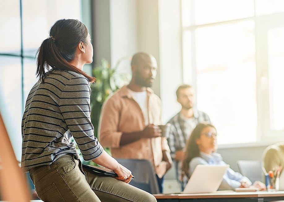 A young woman looking at her business team during a meeting in an office. — Kostiantyn Voitenko // Shutterstock
