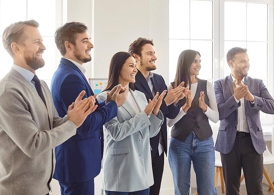 A business team standing and clapping together for a speaker. — Studio Romantic // Shutterstock