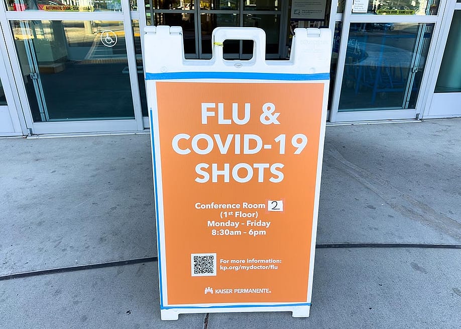 Flu and COVID-19 sign outside a clinic entrance. — 2025 ZikG // Shutterstock
