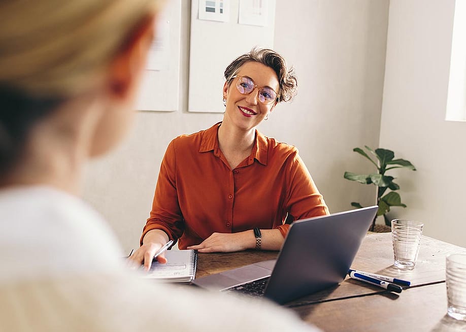 A female hiring manager happily interviewing a job candidate. — Jacob Lund // Shutterstock