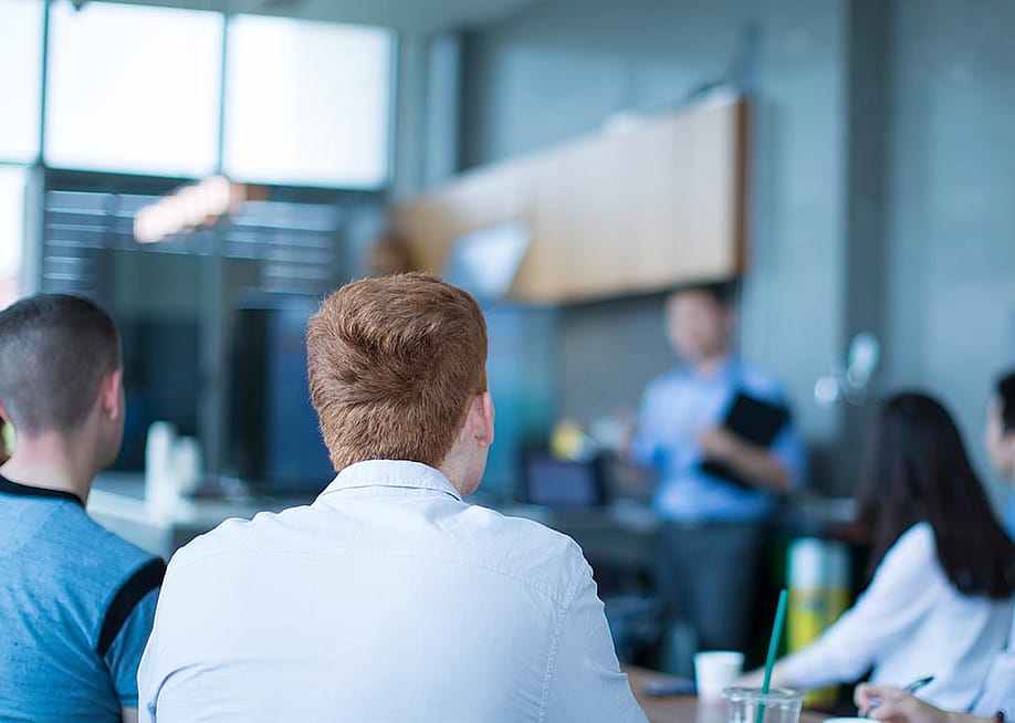 A sales team listening to a presenter in the office. — Life and Times // Shutterstock