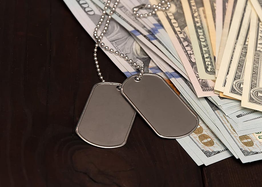 Army badges on top of banknotes as a concept of veterans debt relief. — Anelo // Shutterstock