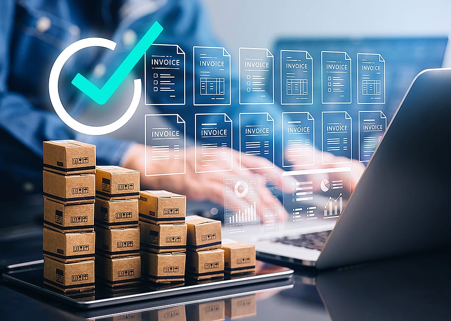 Businessperson using a laptop with small boxes of inventory on the side, illustrated with electric invoice software graphics. — HAKINMHAN // Shutterstock