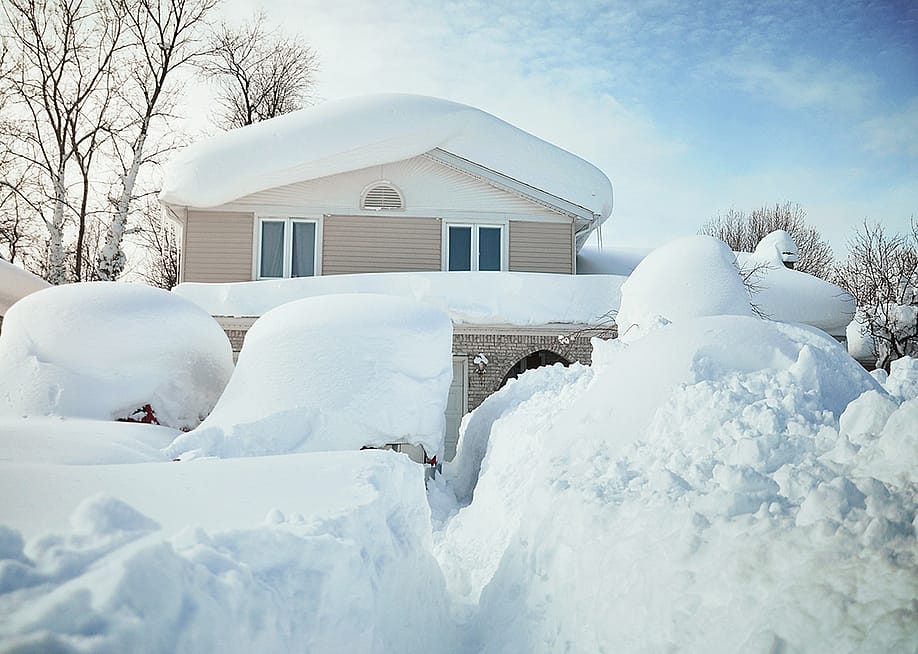 A house and its cars covered in deep white snow after a blizzard. — Creative.Buffalo // Shutterstock