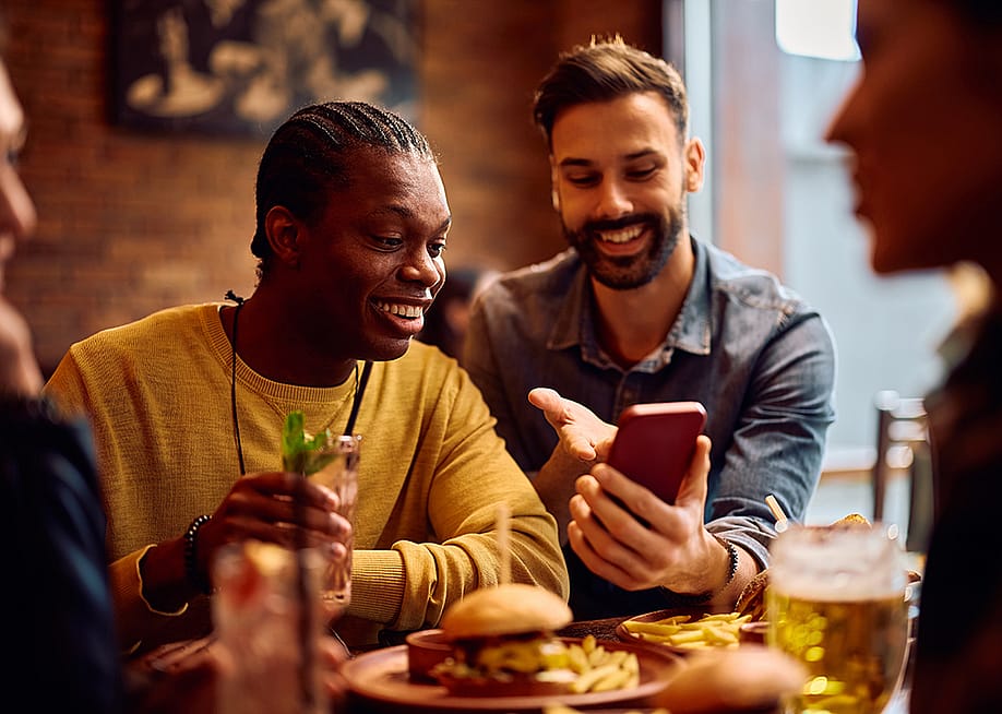 Happy men looking on their phones while sitting in a bar. — Drazen Zigic // Shutterstock