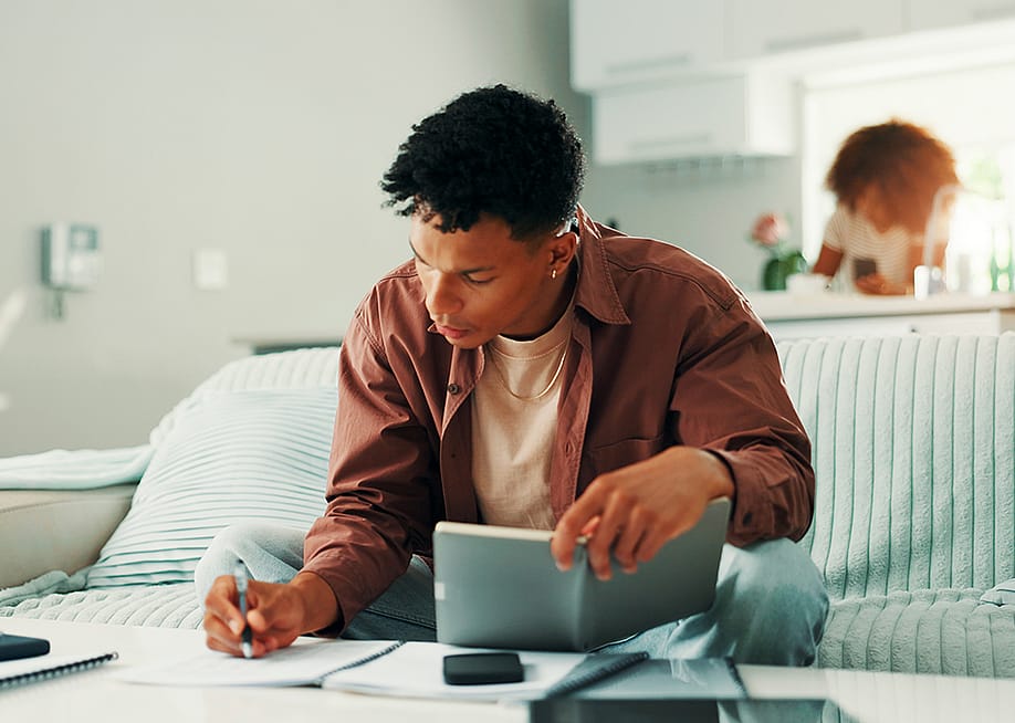 Young man noting expenses and managing finances at home. — PeopleImages // Shutterstock