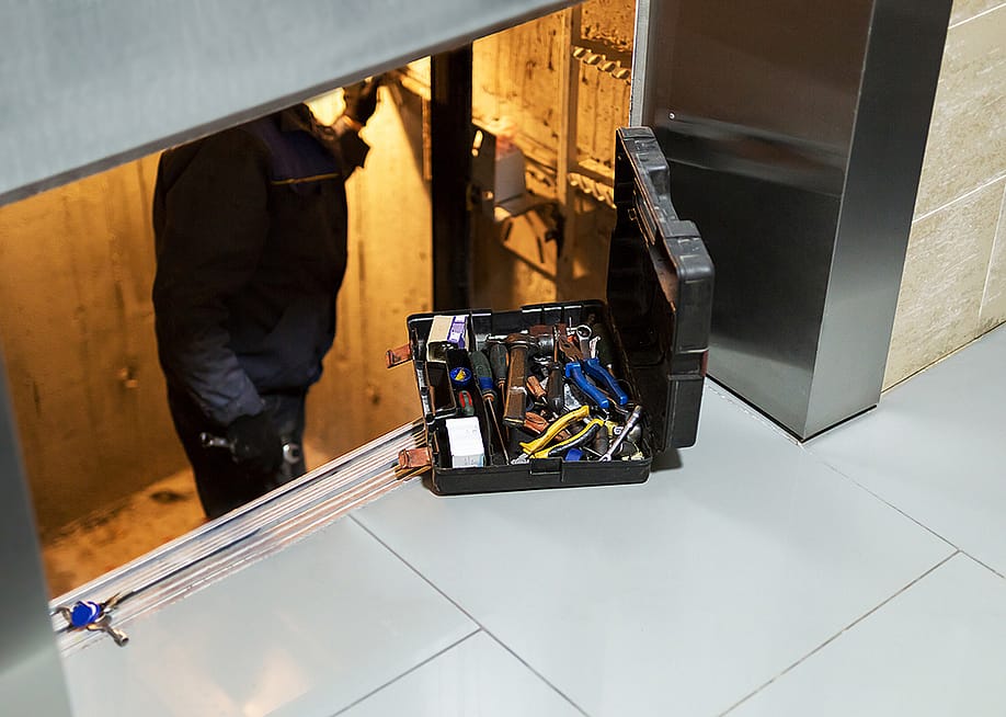 A specialist inside an elevator shaft to repair systems. — K-FK // Shutterstock