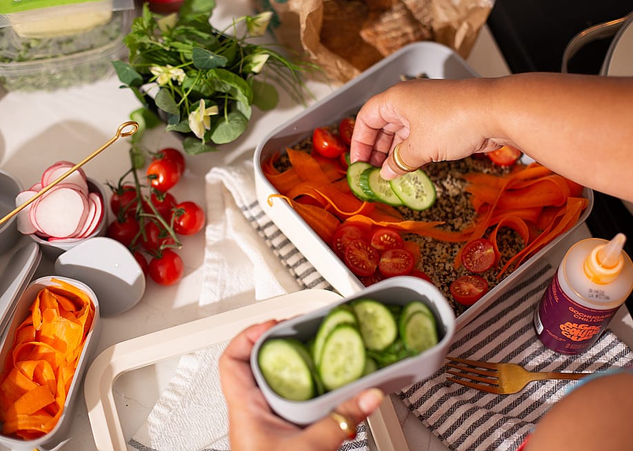 Vegetables being added on top of a healthy meal prep dish. — Christine Shields // Shutterstock