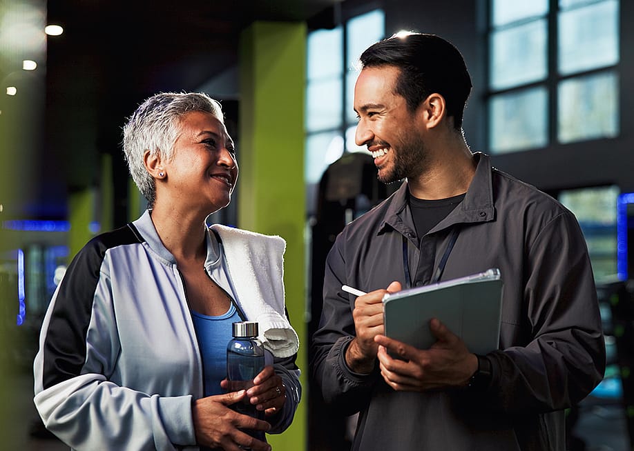 A middle aged woman with her gym trainer. — PeopleImages // Shutterstock