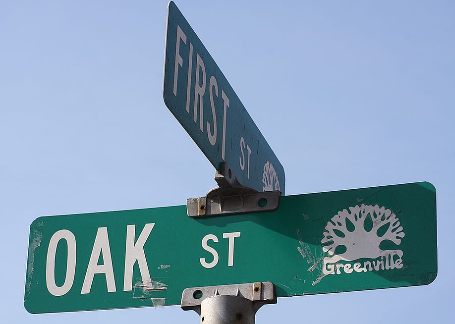 An intersection sign for a First Street and Oak Street. — 10 Cows Photos // Shutterstock