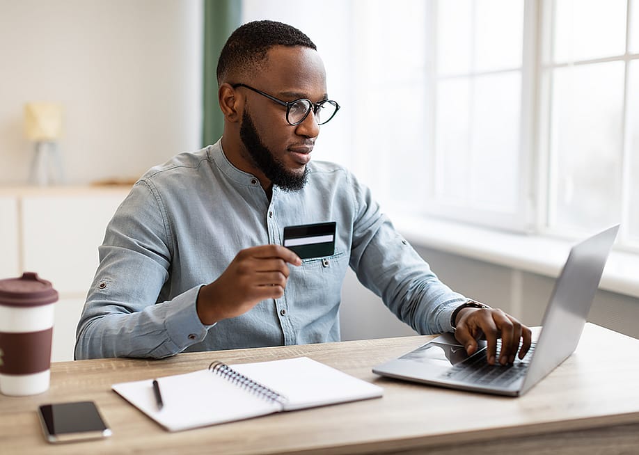 A black businessman using credit card to purchase online while in the office. — Prostock-studio // Shutterstock