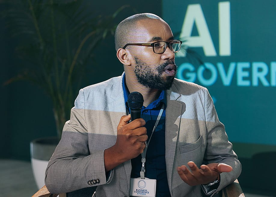 A black businessman giving a presentation on AI governance in a conference. — PeopleImages // Shutterstock