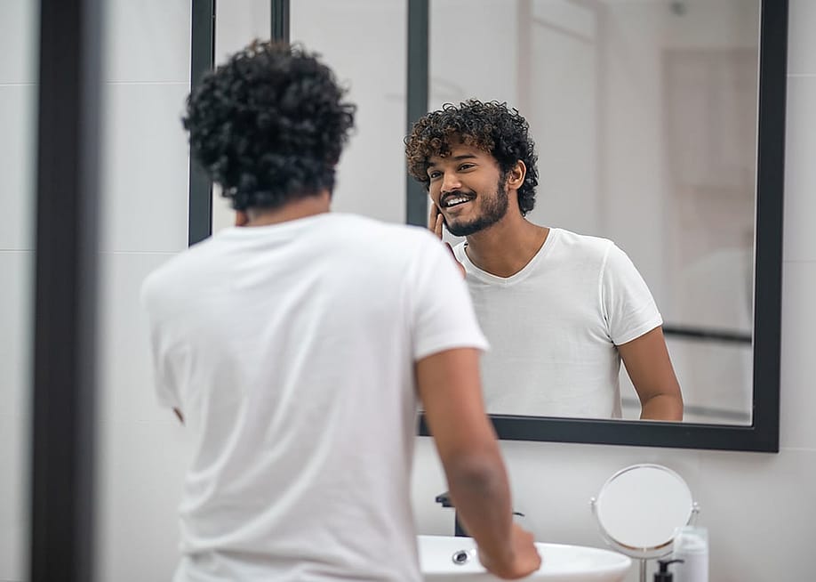 A young man looking at the mirror being pleased with himself. — Dmytro Zinkevych // Shutterstock