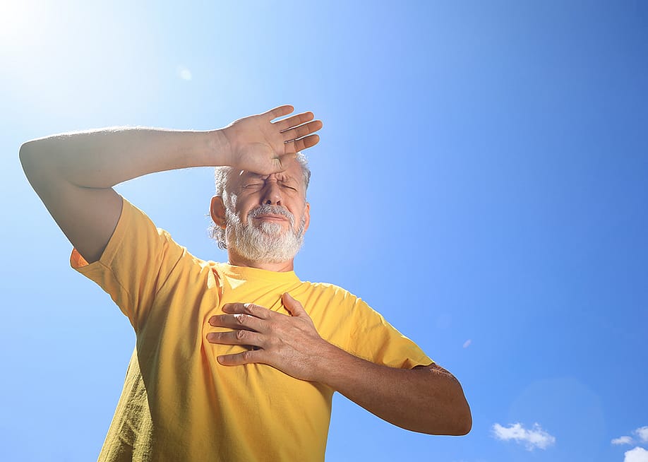 A senior man suffering from heat stroke while outdoors under the sun. — New Africa // Shutterstock