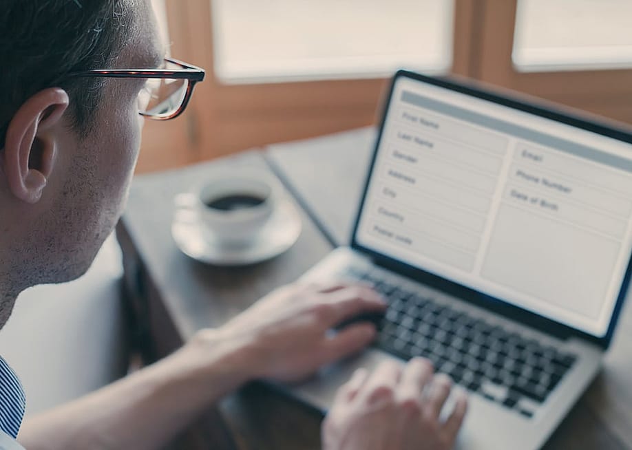 Man using laptop at home to fill out a form online. — Song_about_summer // Shutterstock