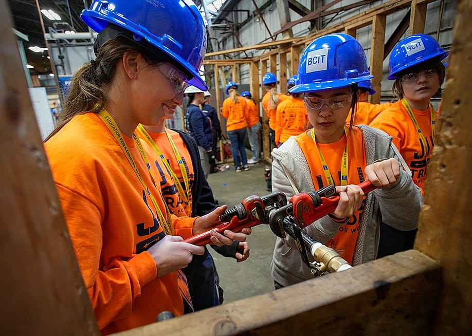 A group of female high school students participating in a skills trade workshop. — Harrison Ha // Shutterstock