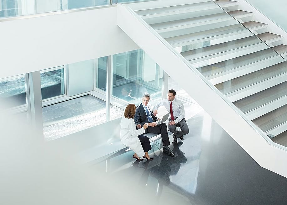 A doctor and administrators talking in a hospital lobby. — KOTOIMAGES // Shutterstock
