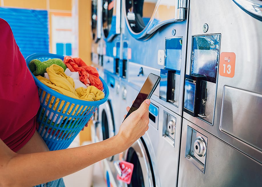 A young woman paying for a laundromat using a mobile app. — Roman Zaiets // Shutterstock