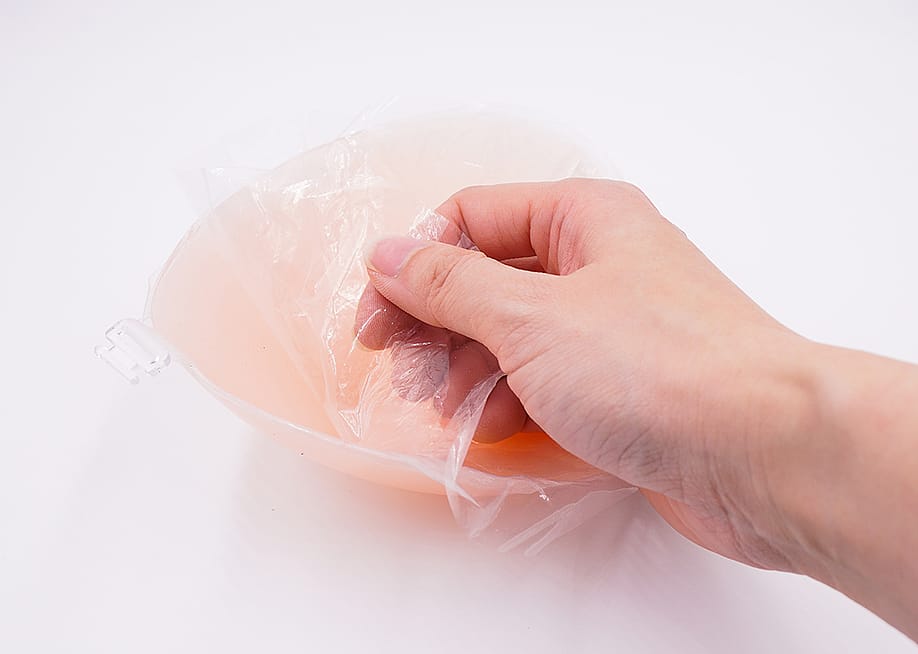 Film adhesive being peeled off a silicone bra pad. — Yoyochow23 // Shutterstock