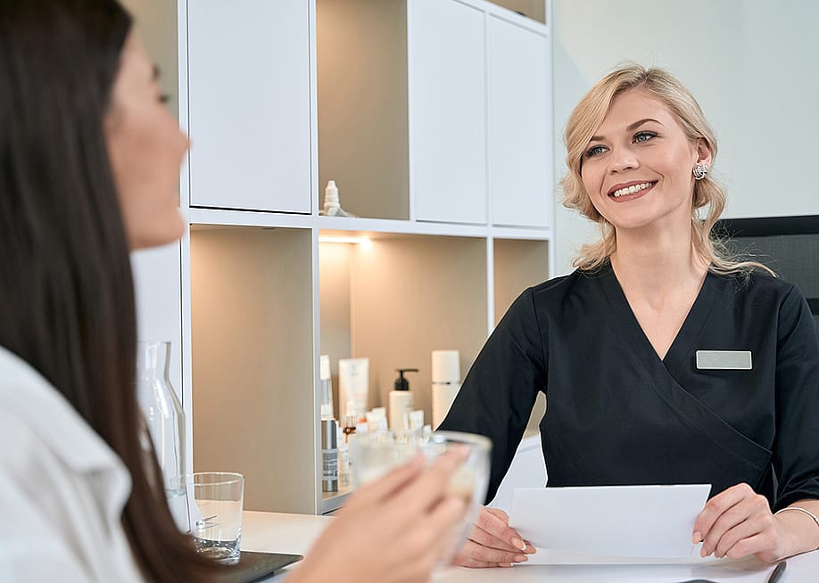 A young woman consulting with a dermatologist at the reception bar of a spa. — Svitlana Hulko // Shutterstock