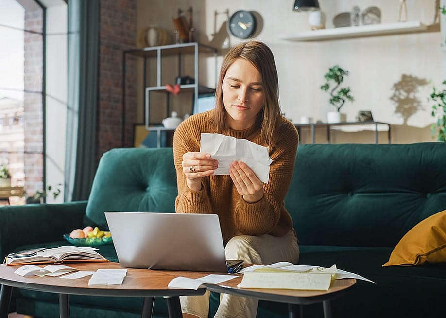 Woman at home looking at receipts. — Gorodenkoff // Shutterstock