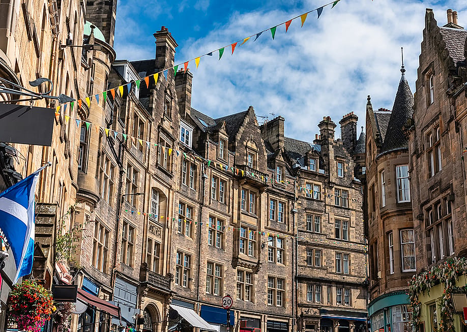 The Old Town street in Edinburgh, Scotland with colorful shops and old stone buildings. — Jose Miguel Sanchez // Shutterstock