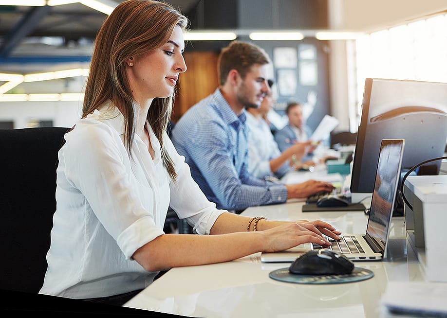 Business employees working in front of computers in their office. — PeopleImages // Shutterstock