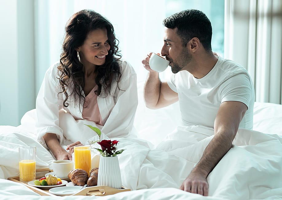 A young couple having breakfast in bed during their honeymoon. — Stock Unit // Shutterstoc