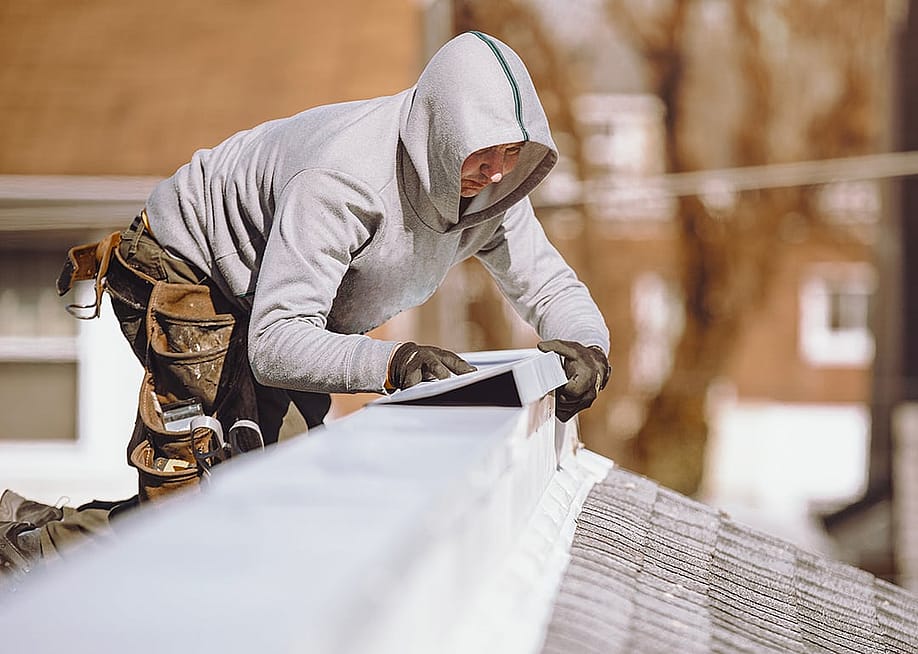 A repairman putting a metal ridge on top of a roof. — Ann Kapustina // Shutterstock