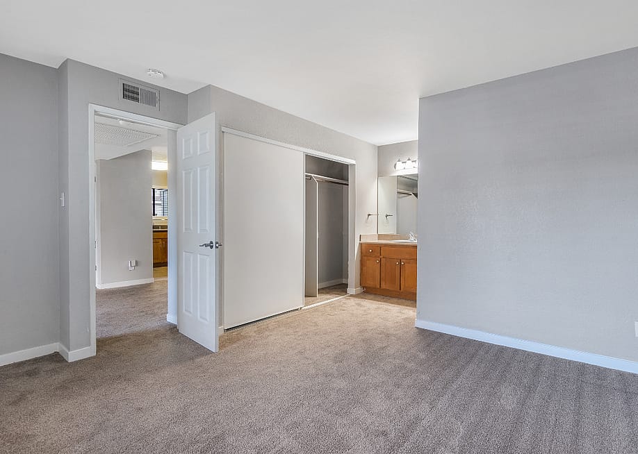 Interior views of an unfurnished apartment unit featuring carpeted bedrooms, built-in vanities, and a gray wall color. — NorCalStockMedia // Shutterstock