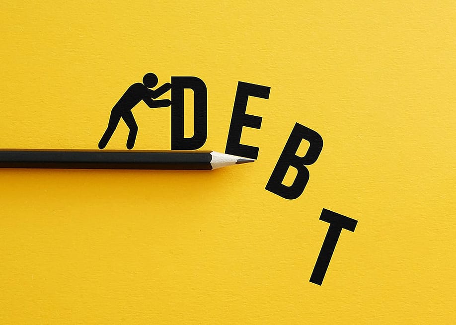 Man pushing away figures of the letters "D, E, B, T" as a concept of relieving debt. — Jack_the_sparow // Shutterstock
