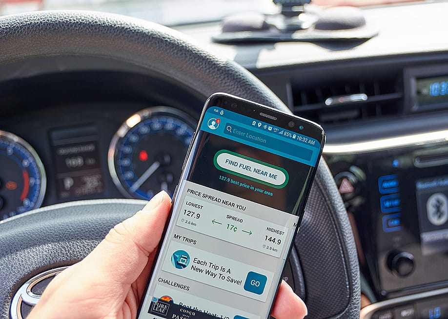 A 'find fuel near me' app displayed on a driver's smartphone while inside the car. — dennizn // Shutterstock