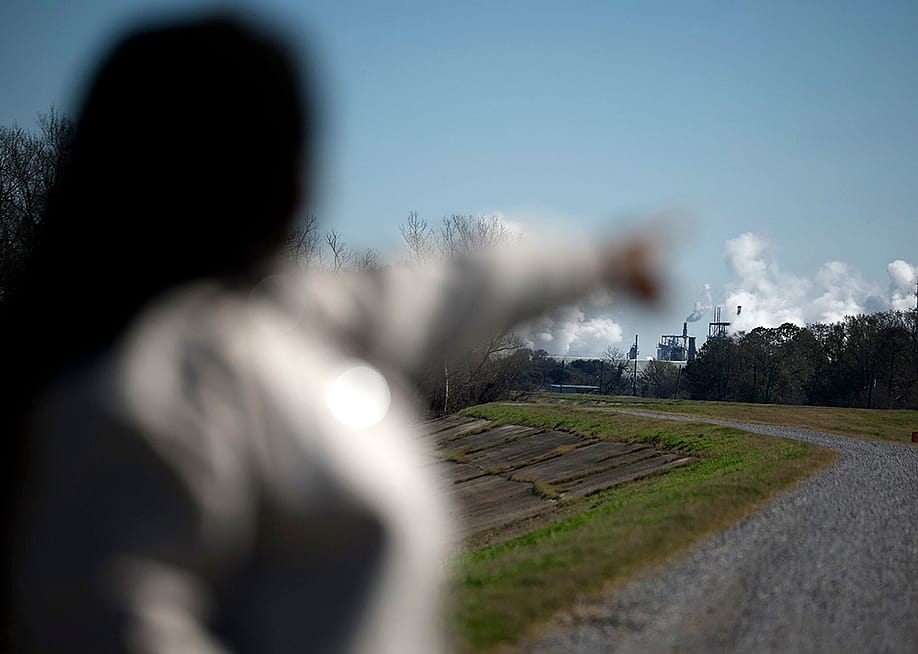 Ashley Gaignard points toward the CF Industries smoke stacks in Donaldsonville, La. That plant emits more air pollutants than all but one other facility nationwide, EPA data show. — Sean Gardner for Floodlight