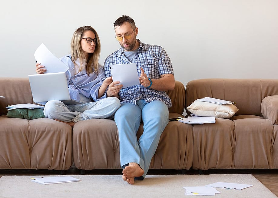 A couple reviewing documents at home. — Green Elk // Shutterstock
