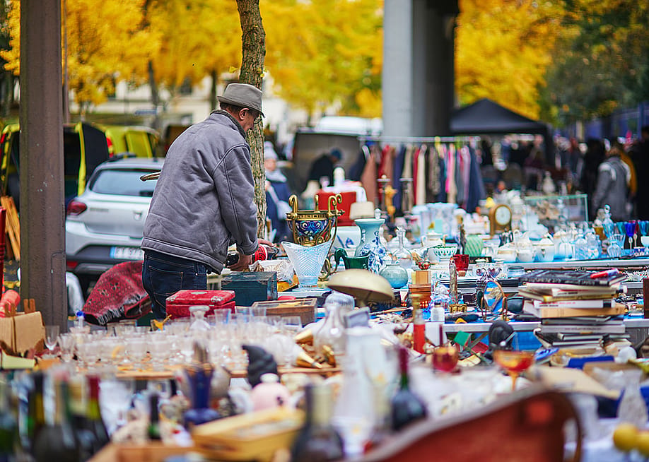 A seller preparing antique items for sale at a flea market in Paris, France. — Ekaterina Pokrovsky // Shutterstock
