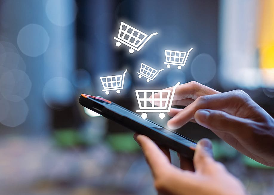 Shopping cart icons over a person using a shopping app on a smartphone. — FOTO Eak // Shutterstock