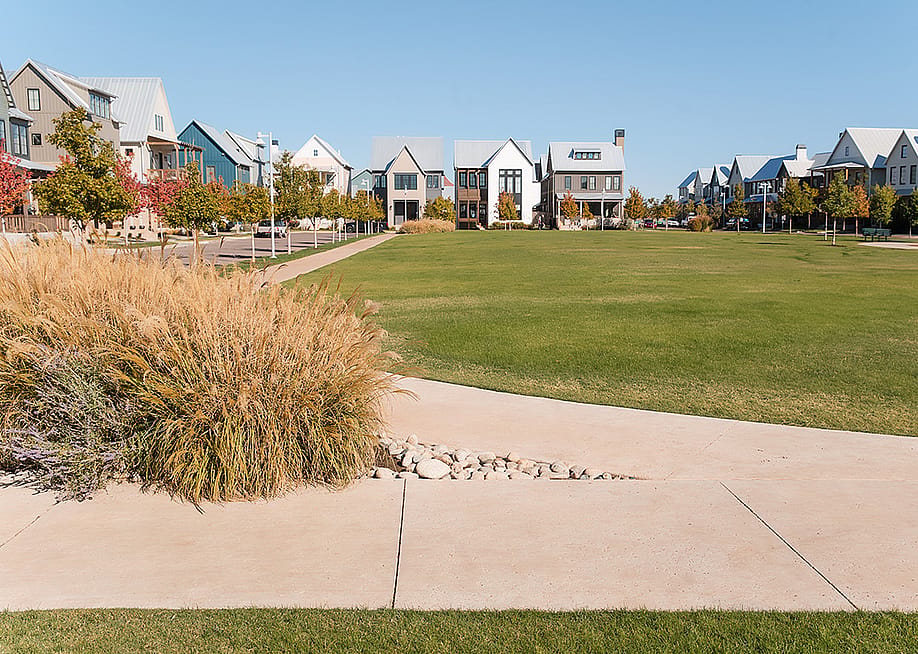 Grassy neighborhood park surrounded by modern homes and sidewalks in Oklahoma City. — Cavan-Images // Shutterstock