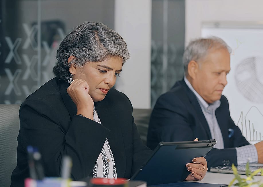 Two senior businesspeople reviewing reports at an office. — Raushan_films // Shutterstock