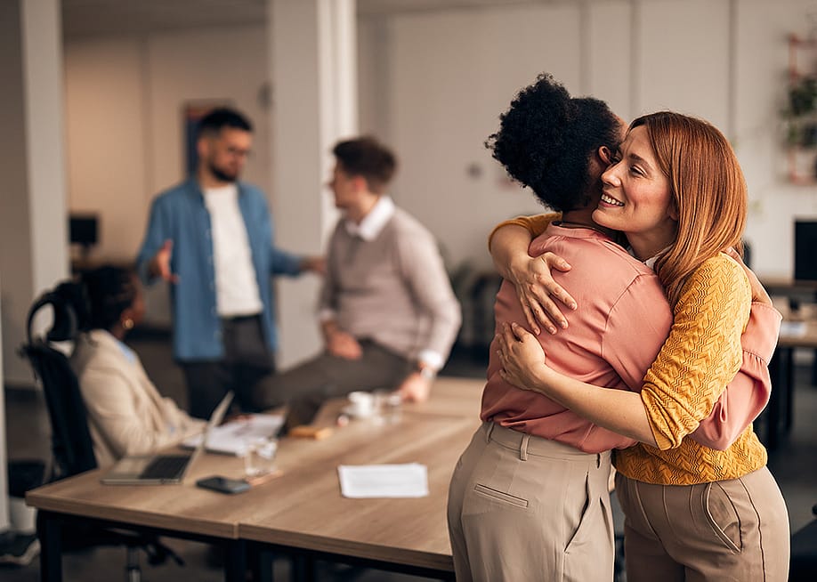 An office worker embracing a colleague. — Jelena Zelen // Shutterstock