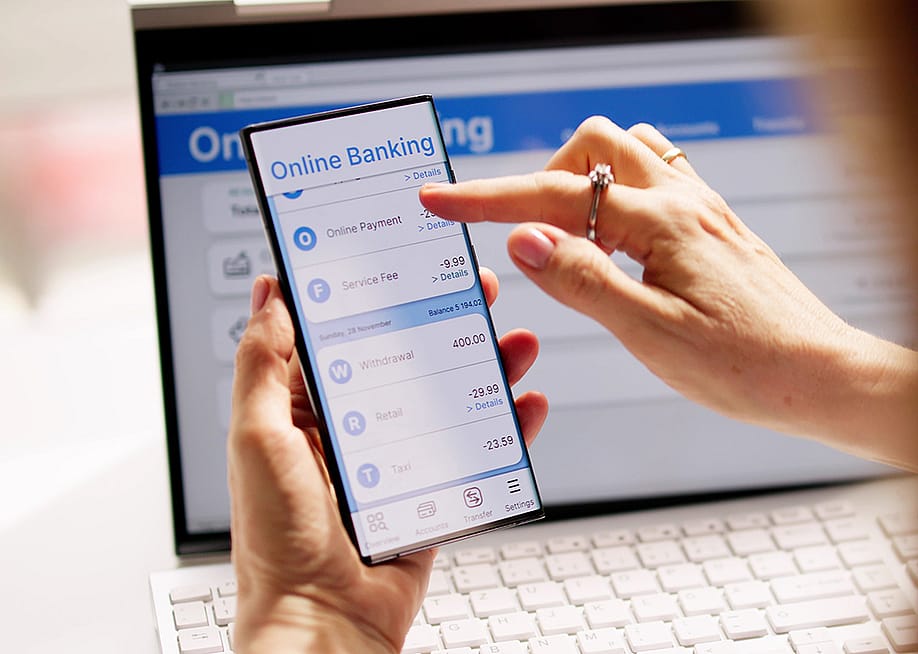 Person using online banking on a smartphone and laptop. — Andrey_Popov // Shutterstock
