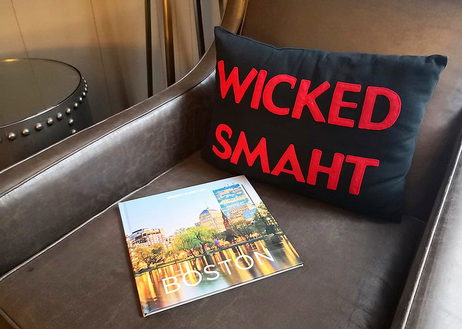A 'wicked smaht' pillow merchandise beside a travel magazine about Boston, Massachusetts. — starlings_images // Shutterstock